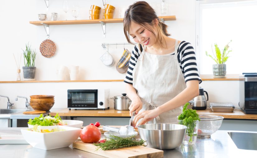 写真：キッチンで野菜をきっている女性